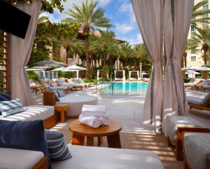 西棕榈滩西棕榈滩希尔顿酒店的酒店庭院设有游泳池和桌椅
