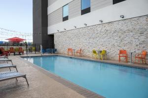 卡尔曼Home2 Suites By Hilton Cullman的一座带橙色和蓝色椅子的游泳池以及一座建筑