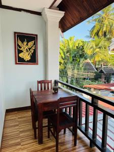 琅勃拉邦Singrarat Hotel的阳台的用餐室配有桌椅
