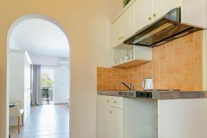 古维亚Porto Marina Aparthotel的一间厨房,配有白色的橱柜和拱门