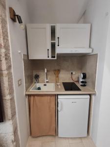 普蒂尼亚诺Archi Antichi的小厨房配有白色橱柜和水槽