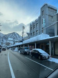 汤泽町駅本ビル民宿的一条雪 ⁇ 的街道,路边停有汽车