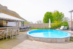 登海尔德Villa Pakhuys - groepsaccommodatie - Julianadorp aan Zee的一个带桌椅的游泳池和一个庭院
