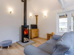 Wootton Glanville1 bed in Sherborne 80737的客厅配有蓝色的沙发和燃木炉。