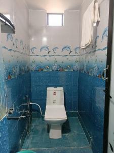 乌贾因Aarav Home Stay的一间带卫生间的浴室和蓝色瓷砖墙