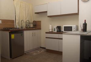 拉利伯塔德Sunset View - Mini Loft的厨房配有白色橱柜和微波炉