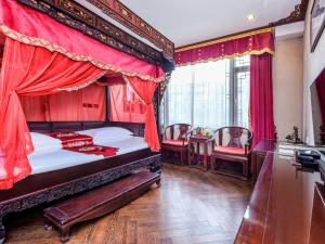成都汉室酒店(成都锦里武侯祠店)的一间卧室配有一张带红色窗帘的天蓬床