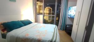 马尼拉Aveline Suites Cozy Skyline View ACQUA Private Residences near Rockwell Makati的一间卧室设有一张床和一个带电视的窗户。