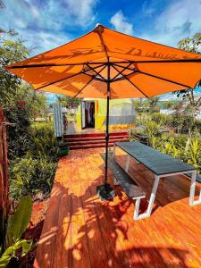 Véal VêngKravanh Camping Cardamom Mountain的甲板上橘色伞下的长凳