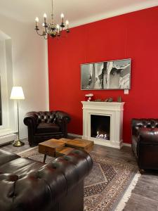 普尔斯尼茨Waldhaus Pulsnitz的红色的客厅配有皮革家具和壁炉