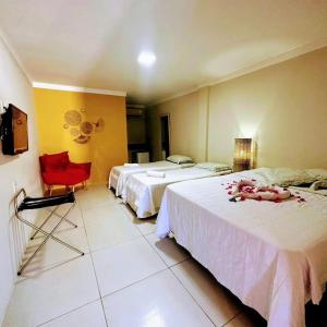 ExtremózPOUSADA GENIPABU PRAIA的酒店客房,设有两张床和一张红色椅子