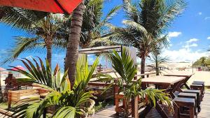 ExtremózPOUSADA GENIPABU PRAIA的棕榈树海滩,海滩上摆放着桌椅