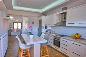 圣斯特凡诺斯Elena Luxury Suite Agios Stefanos的厨房配有白色橱柜和桌椅
