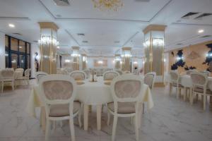 BotizHotel Restaurant Imperium的一间设有白色桌椅的用餐室