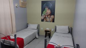 沃尔塔雷东达Pousada Das Camelias的一间设有两张床的客房,墙上挂着一幅画
