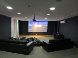 佩德拉阿祖尔Suíte Vista Azul - Frente para Pedra Azul的客厅配有两张黑色沙发和大屏幕电视