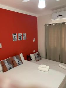 卡拉瓜塔图巴Pousada Recanto Som do Mar的卧室配有白色的床和红色的墙壁