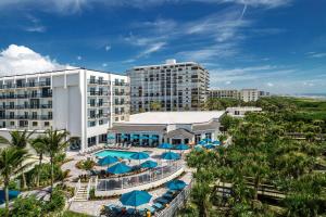 可可比奇Hilton Garden Inn Cocoa Beach-Oceanfront, FL的享有带游泳池和遮阳伞的度假村的空中景致