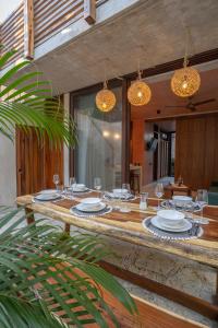图卢姆Entorno Tulum - Luxury Villas的一张木桌,上面有玻璃杯和盘子