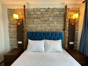 埃杰阿巴德İLİA BUTİK OTEL的一张带蓝色床头板和砖墙的床