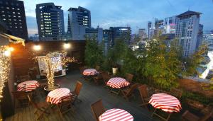 首尔空中花园酒店明洞1号店的一个带桌椅的屋顶露台,享有城市天际线