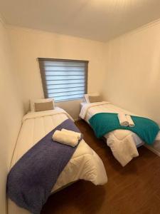 纳塔列斯港Tú Casa en Puerto Natales的带窗户的客房内设有两张单人床。