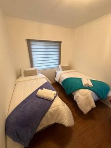 纳塔列斯港Tú Casa en Puerto Natales的带窗户的客房内设有两张单人床。