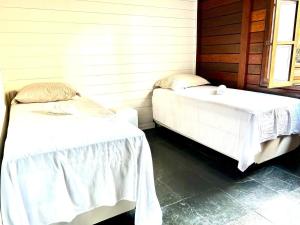 瓜鲁柳斯Pousada Casa da Noiva的配有白色床单的客房内的两张床