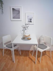 维尔茨堡nette 1 Zimmerwohnung in Würzburg的白色的餐桌和两把椅子,花瓶