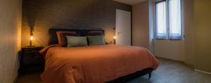 RougegoutteGîte l'escapade 90的一间卧室配有一张带橙色毯子和窗户的床。