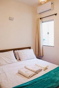 阿拉亚尔达茹达Residencial Ilha do Sol的一张带两条毛巾的床和窗户