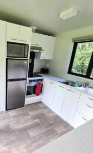 帕拉帕拉乌穆Private Country Cottage的厨房配有白色橱柜和不锈钢冰箱
