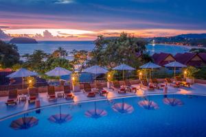 卡塔海滩Chanalai Garden Resort, Kata Beach的黄昏时分酒店带椅子和遮阳伞的游泳池