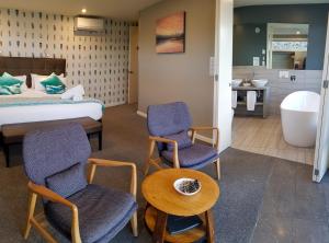 普卡基湖湖石山林小屋的酒店客房配有一张床、两把椅子和一个浴缸