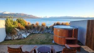 普卡基湖湖石山林小屋的热水浴池位于带椅子的房屋的一侧