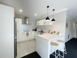汉密尔顿Modern and Comfortable Home in Flagstaff的白色的厨房,配有一个柜台和两个凳子