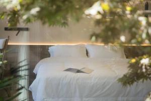 青岛慕野共潮民宿(青岛崂山风景区仰口店)的卧室配有一张白色的床,上面有书