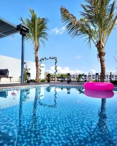 富查伊拉Al Dana Paradise Luxury Villas Palm Fujairah Sea View的一座棕榈树和粉红色浮子的游泳池