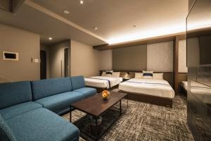 鹿儿岛GRAND BASE Kagoshima Tenmonkan的酒店客房,设有两张床和一张蓝色的沙发