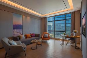 深圳深圳西丽创新谷亚朵酒店的带沙发和椅子的客厅以及大窗户。