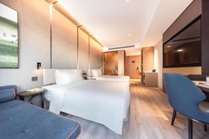 滨海新区天津滨海三大街MSD亚朵酒店的酒店客房设有一张白色大床和一张沙发。