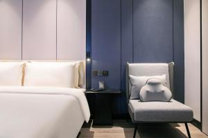 杭州杭州西湖武林广场延安路亚朵X酒店的一间卧室配有两张床和一张带枕头的椅子