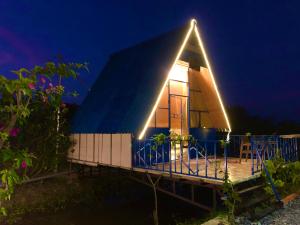 Tây NinhLA'S FARMSTAY的夜晚有三角形屋顶的房子