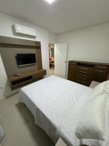 伊塔佩马Apartamento à 390m do Mar的卧室配有白色的床和电视
