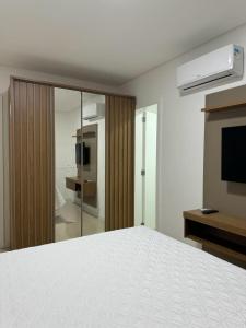 伊塔佩马Apartamento à 390m do Mar的卧室配有白色的床和电视。