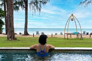 蔻立Khaolak Emerald Surf Beach Resort and Spa的一位在游泳池里看着海滩的女人