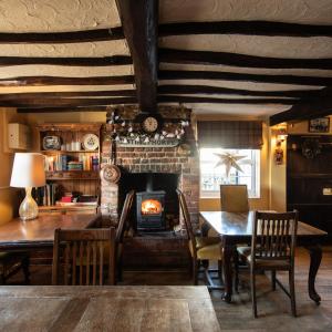 GestingthorpeThe Pheasant Pub at Gestingthorpe Stylish Boutique Rooms in The Coach House的一间带壁炉和桌椅的用餐室