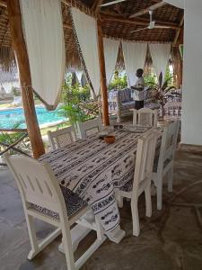 马林迪Cosy Cottage Marine Park at Malindi beach的一张桌子和椅子,一张桌子和一张背景的女人