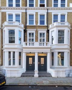 伦敦Earls Court East Serviced Apartments by StayPrime的一座白色的大建筑,设有黑色的门