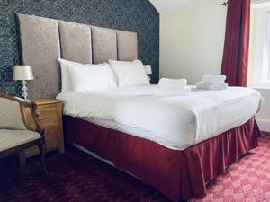 兰迪德诺Merrion Hotel的一张大床,位于酒店带椅子的房间里